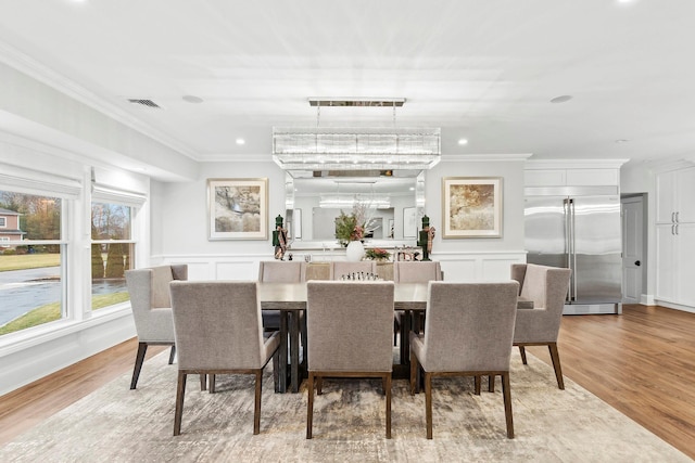 dining area featuring ornamental molding, a chandelier, and light wood-type flooring