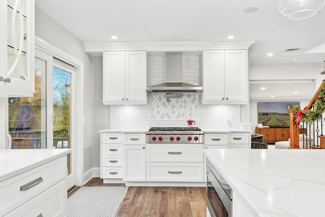 kitchen with wall chimney exhaust hood, white cabinetry, stainless steel gas cooktop, and tasteful backsplash