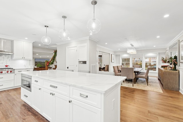 kitchen featuring built in microwave, white cabinetry, backsplash, decorative light fixtures, and light wood-type flooring