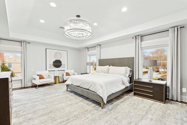 bedroom with a raised ceiling, a chandelier, and light hardwood / wood-style floors