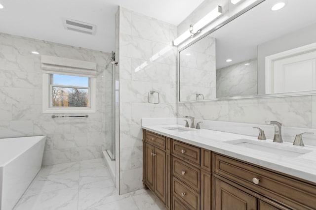 bathroom with vanity, shower with separate bathtub, and tile walls