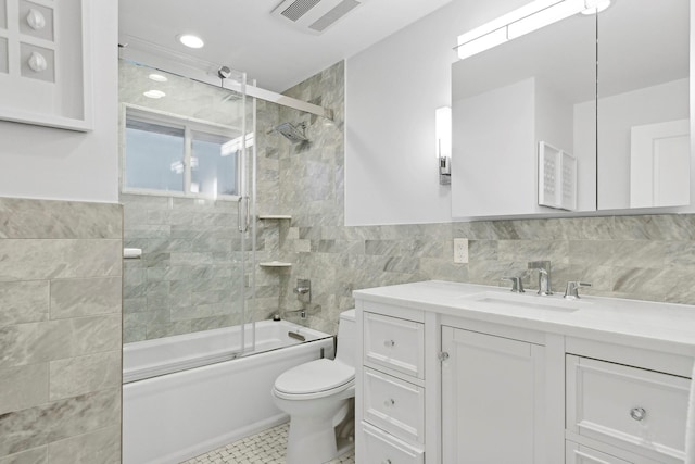 full bathroom featuring combined bath / shower with glass door, tile patterned floors, vanity, tile walls, and toilet