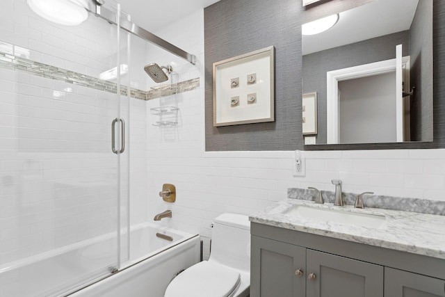 full bathroom featuring vanity, toilet, enclosed tub / shower combo, and tile walls