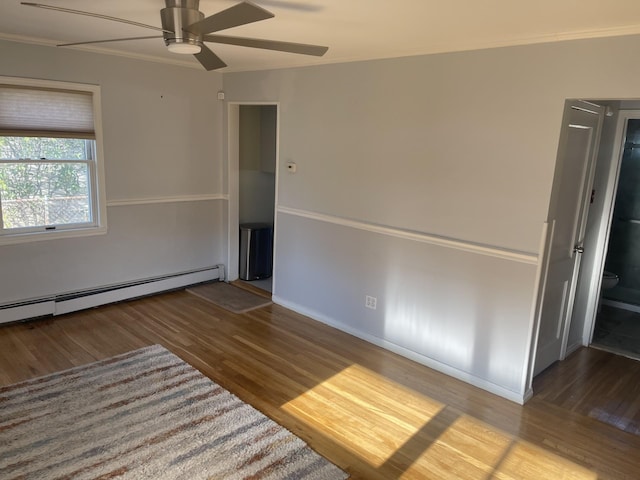 empty room with ceiling fan, ornamental molding, a baseboard heating unit, and hardwood / wood-style flooring