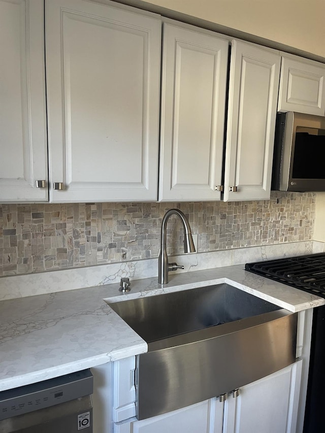 kitchen featuring decorative backsplash, white cabinets, and stainless steel appliances