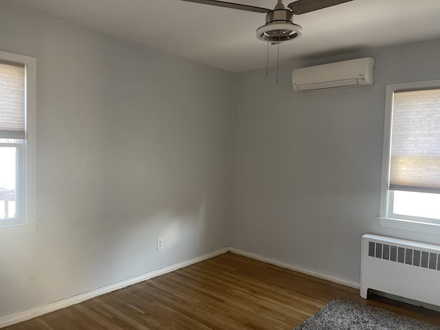 empty room with radiator heating unit, dark hardwood / wood-style flooring, a wall mounted AC, and ceiling fan