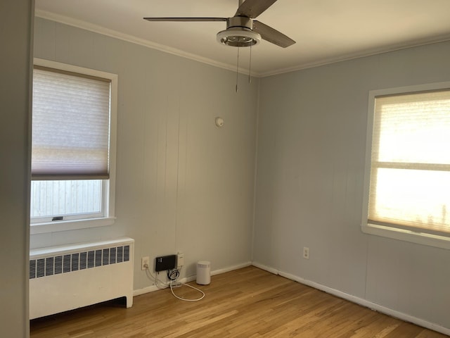 unfurnished room featuring ceiling fan, radiator heating unit, light hardwood / wood-style floors, and ornamental molding