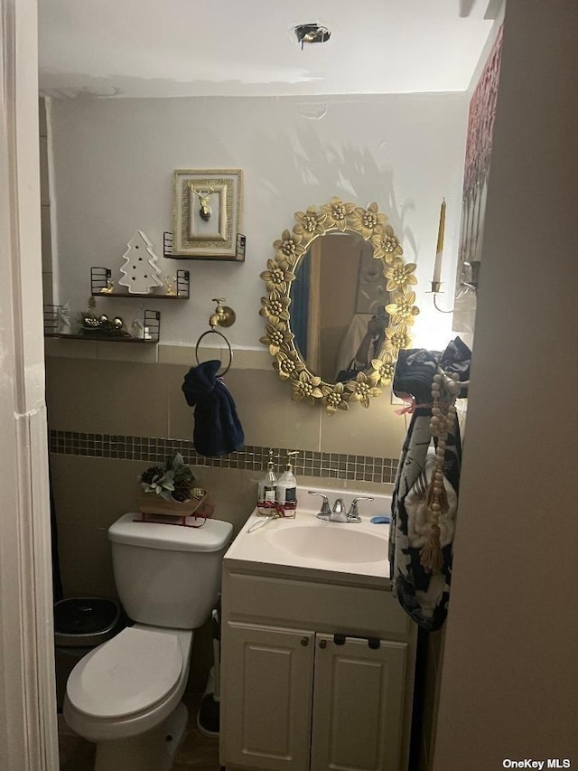 bathroom with vanity, toilet, and tile walls