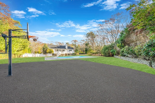 view of basketball court with a lawn and a pool