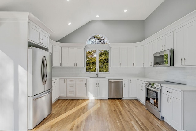 kitchen featuring decorative backsplash, appliances with stainless steel finishes, high vaulted ceiling, light hardwood / wood-style floors, and white cabinetry