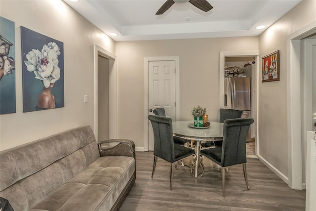 dining area featuring ceiling fan, dark wood-type flooring, and a tray ceiling