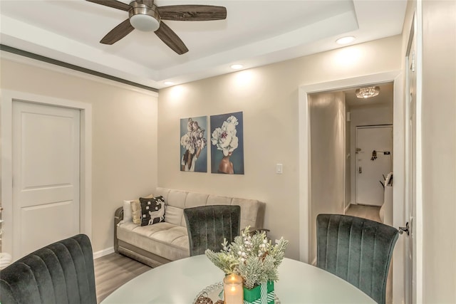 living room featuring a raised ceiling, ceiling fan, and hardwood / wood-style flooring