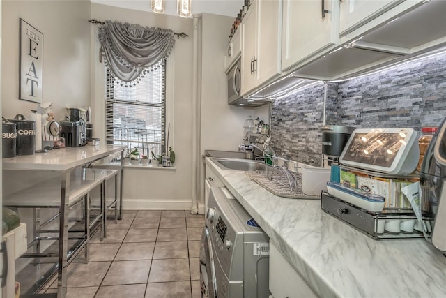 kitchen featuring white cabinetry, sink, tile patterned flooring, backsplash, and washer / dryer