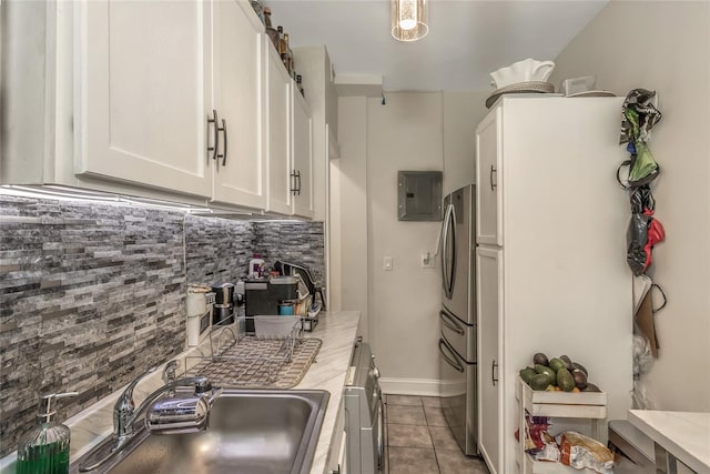 kitchen featuring sink, a barn door, stainless steel fridge, decorative backsplash, and white cabinets