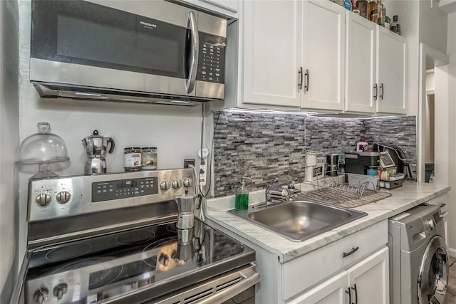 kitchen with tasteful backsplash, stainless steel appliances, sink, washer / clothes dryer, and white cabinetry