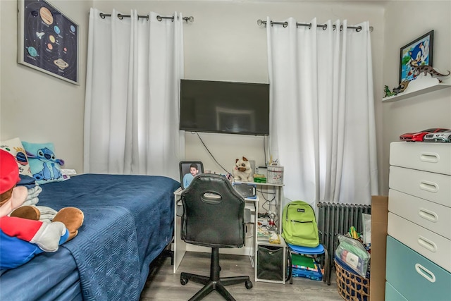 bedroom featuring hardwood / wood-style floors and radiator heating unit