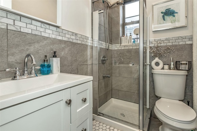 bathroom featuring vanity, toilet, a shower with shower door, and tile walls