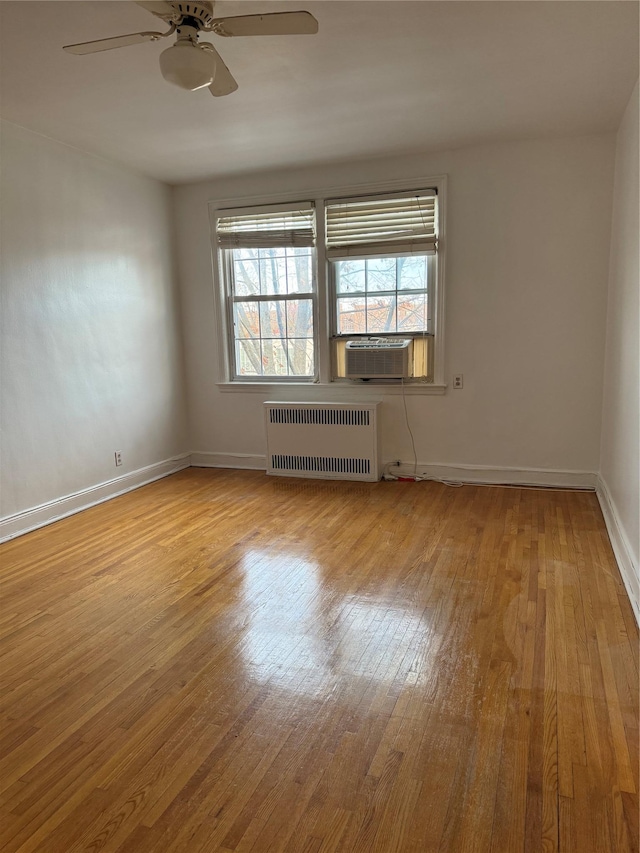 empty room featuring ceiling fan, radiator heating unit, cooling unit, and light hardwood / wood-style flooring