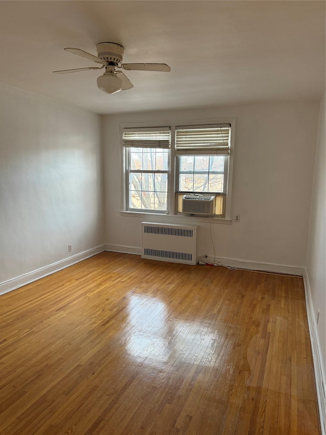 unfurnished room with ceiling fan, radiator heating unit, cooling unit, and light hardwood / wood-style floors