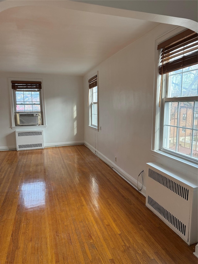 unfurnished living room featuring hardwood / wood-style floors, radiator, and cooling unit