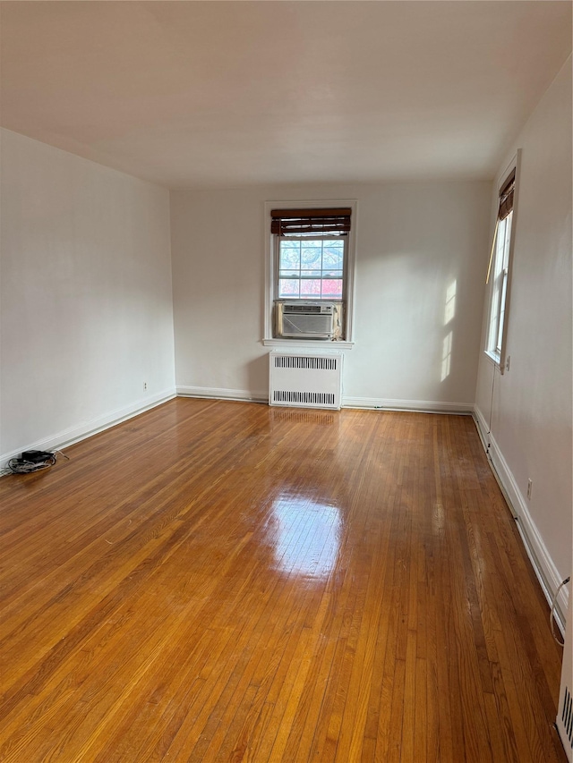 unfurnished living room featuring radiator, cooling unit, and wood-type flooring