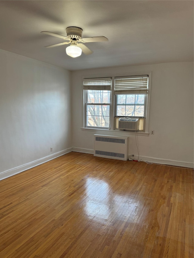 spare room featuring ceiling fan, cooling unit, radiator heating unit, and light hardwood / wood-style flooring