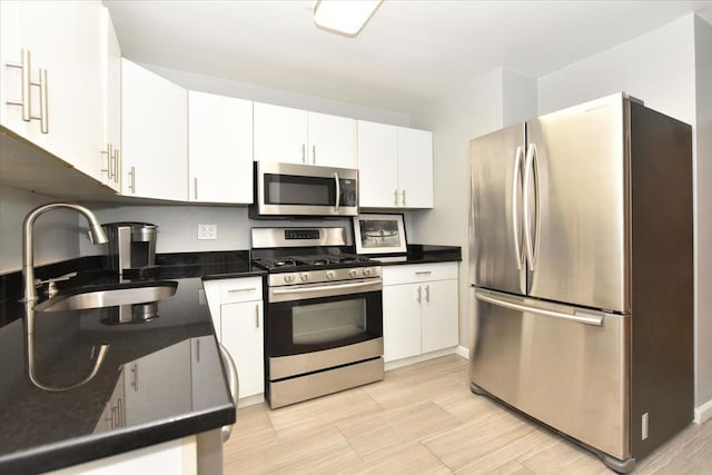 kitchen featuring appliances with stainless steel finishes, white cabinetry, and sink