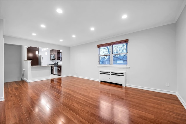 unfurnished living room featuring radiator and wood-type flooring