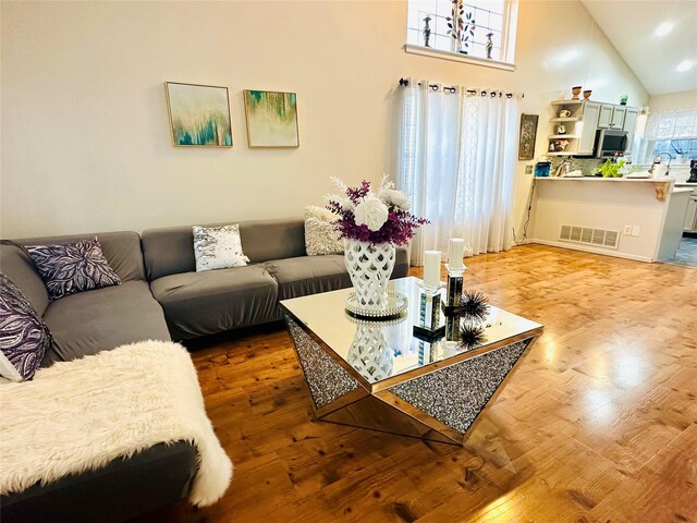 living room with high vaulted ceiling and wood-type flooring