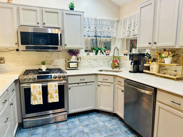 kitchen featuring white cabinetry, sink, light tile patterned floors, and stainless steel appliances