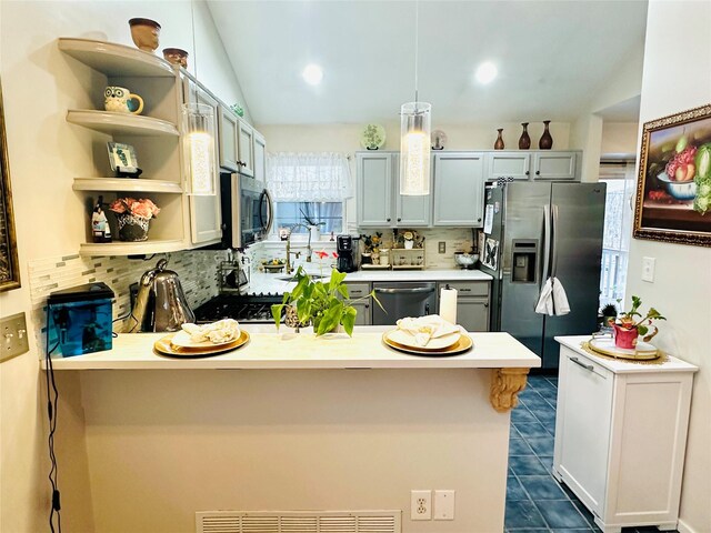 kitchen featuring lofted ceiling, stainless steel appliances, hanging light fixtures, and tasteful backsplash