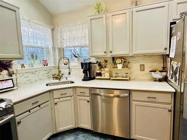 kitchen with lofted ceiling, sink, appliances with stainless steel finishes, and tasteful backsplash