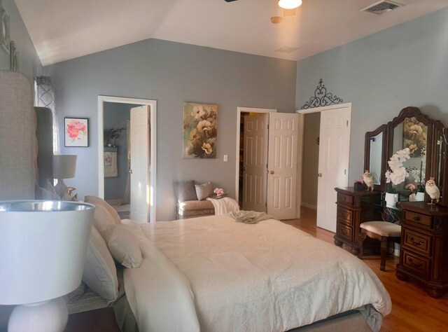 bedroom featuring light wood-type flooring, ensuite bathroom, and lofted ceiling