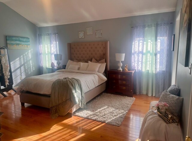 bedroom with light hardwood / wood-style floors and lofted ceiling