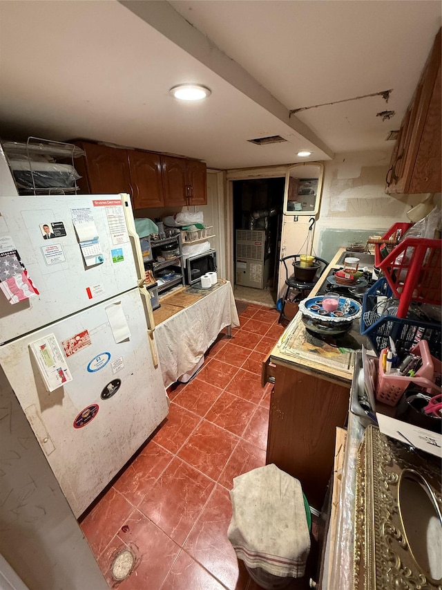 kitchen with dark tile patterned floors and white fridge