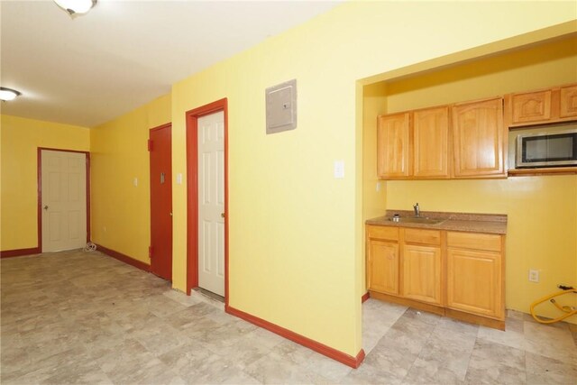 kitchen with electric panel, sink, and light brown cabinetry