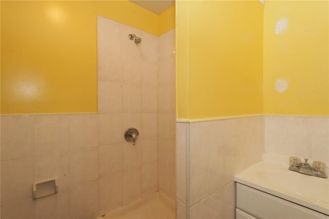 bathroom featuring vanity, a tile shower, and tile walls