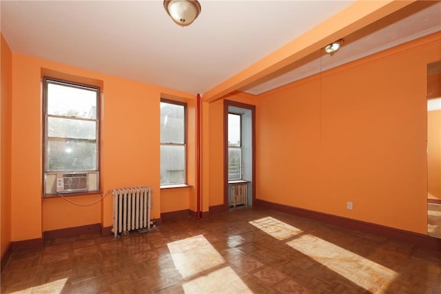 empty room featuring dark parquet floors, cooling unit, and radiator