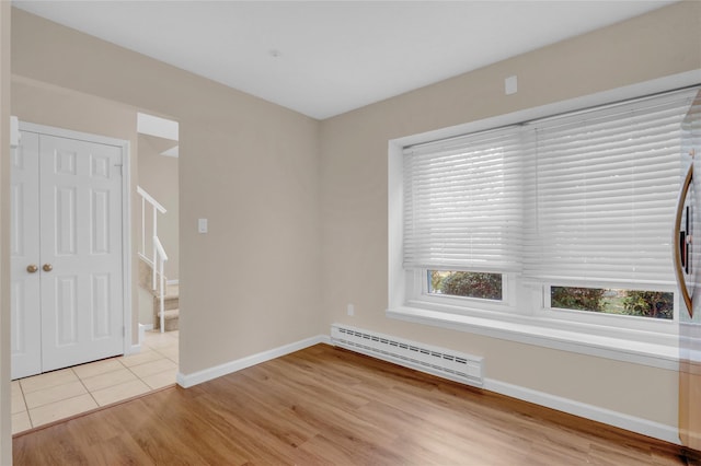 empty room featuring a baseboard radiator and light hardwood / wood-style floors