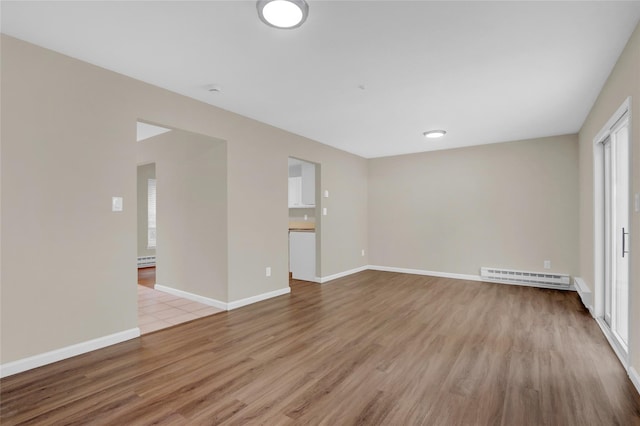 empty room featuring light hardwood / wood-style floors and a baseboard heating unit