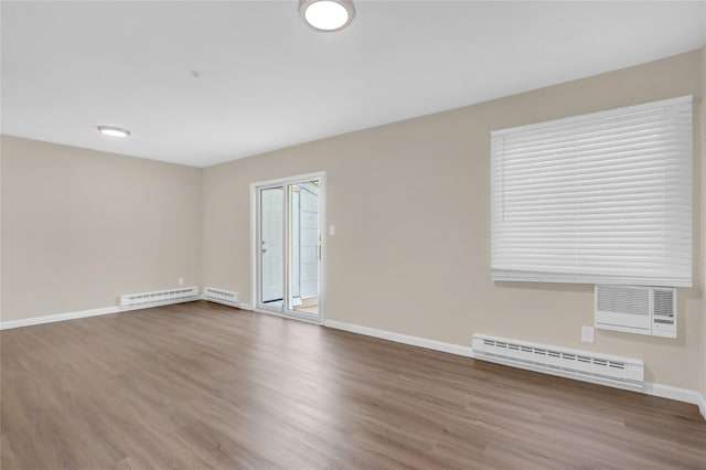 spare room featuring a wall mounted air conditioner, wood-type flooring, and baseboard heating