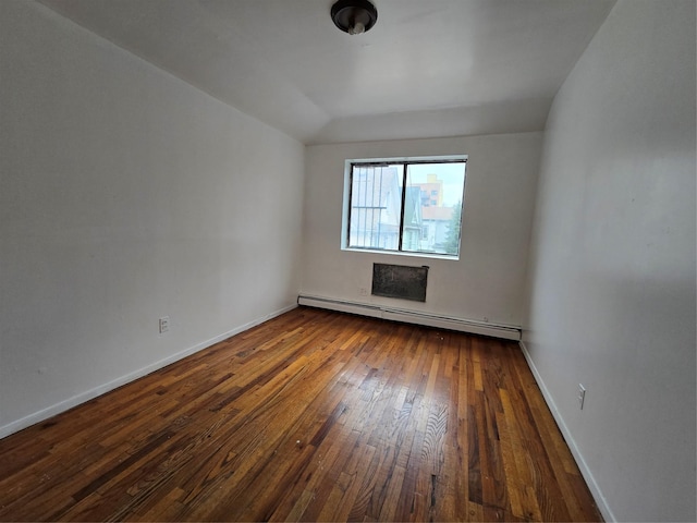 spare room featuring wood-type flooring, baseboards, and a baseboard heating unit