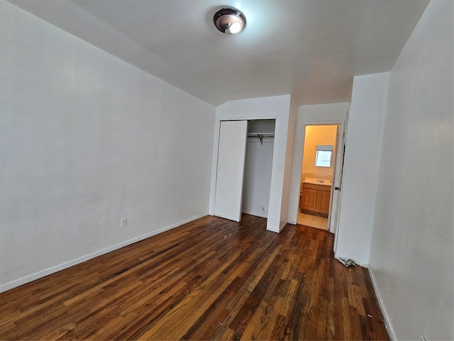 unfurnished bedroom with a closet, dark wood-style flooring, and baseboards