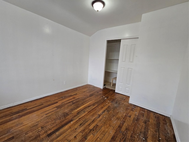 unfurnished bedroom with baseboards, lofted ceiling, a closet, and wood-type flooring
