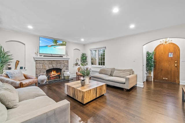 living room with a notable chandelier, a stone fireplace, and dark hardwood / wood-style flooring