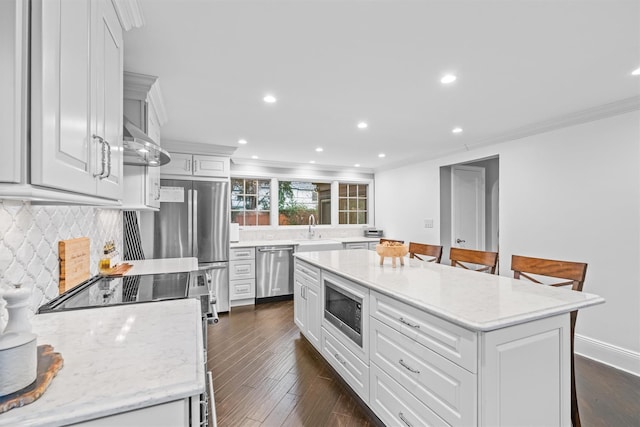 kitchen with a kitchen breakfast bar, a center island, appliances with stainless steel finishes, and dark wood-type flooring