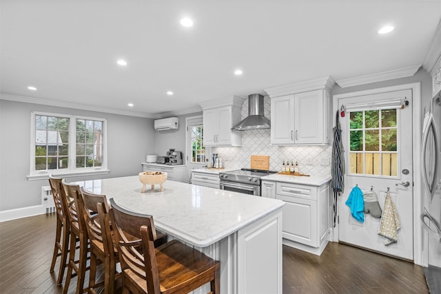 kitchen with white cabinets, a center island, stainless steel appliances, and wall chimney exhaust hood