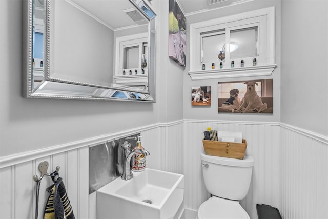 bathroom with toilet, ornamental molding, and sink