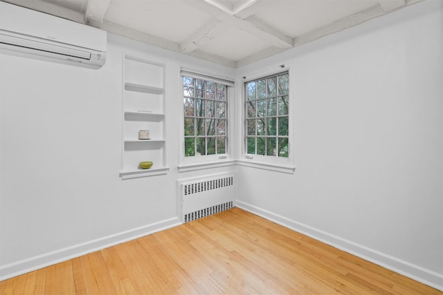 empty room with hardwood / wood-style floors, beam ceiling, radiator, and a wall mounted AC