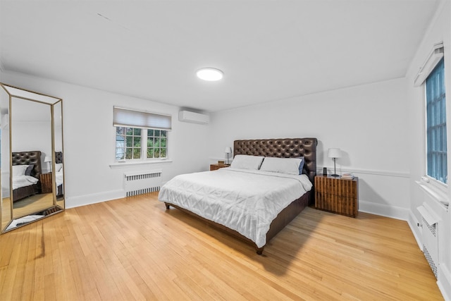 bedroom featuring radiator heating unit, a wall mounted AC, and wood-type flooring